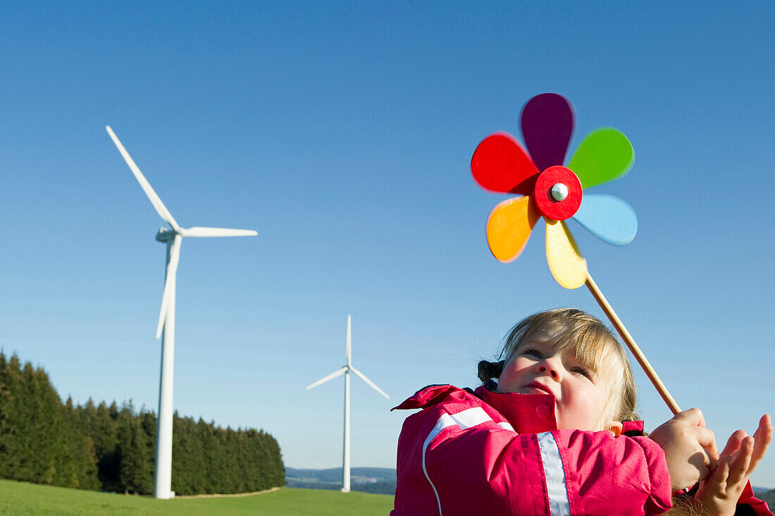 Little girl with toy windmill, wind turbine in the background, Black Forest, Baden-Wurttemberg, Germany