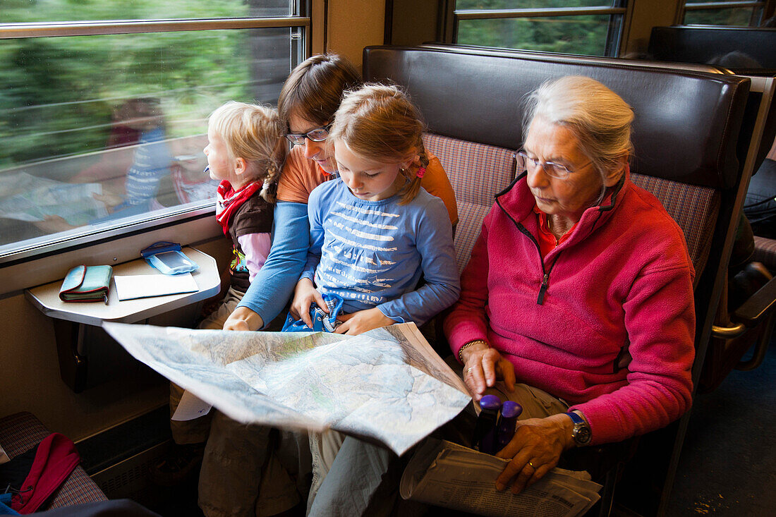Two girls, a young and an older woman are sitting in a train, Switzerland.