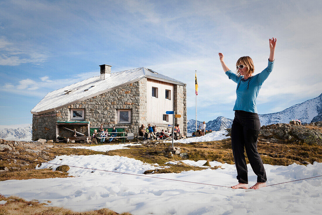 A woman balancing on a slackline at the Sewenhut, SAC, Swiss Alpine-Club, Swiss Alps, Kanton Uri, Switzerland
