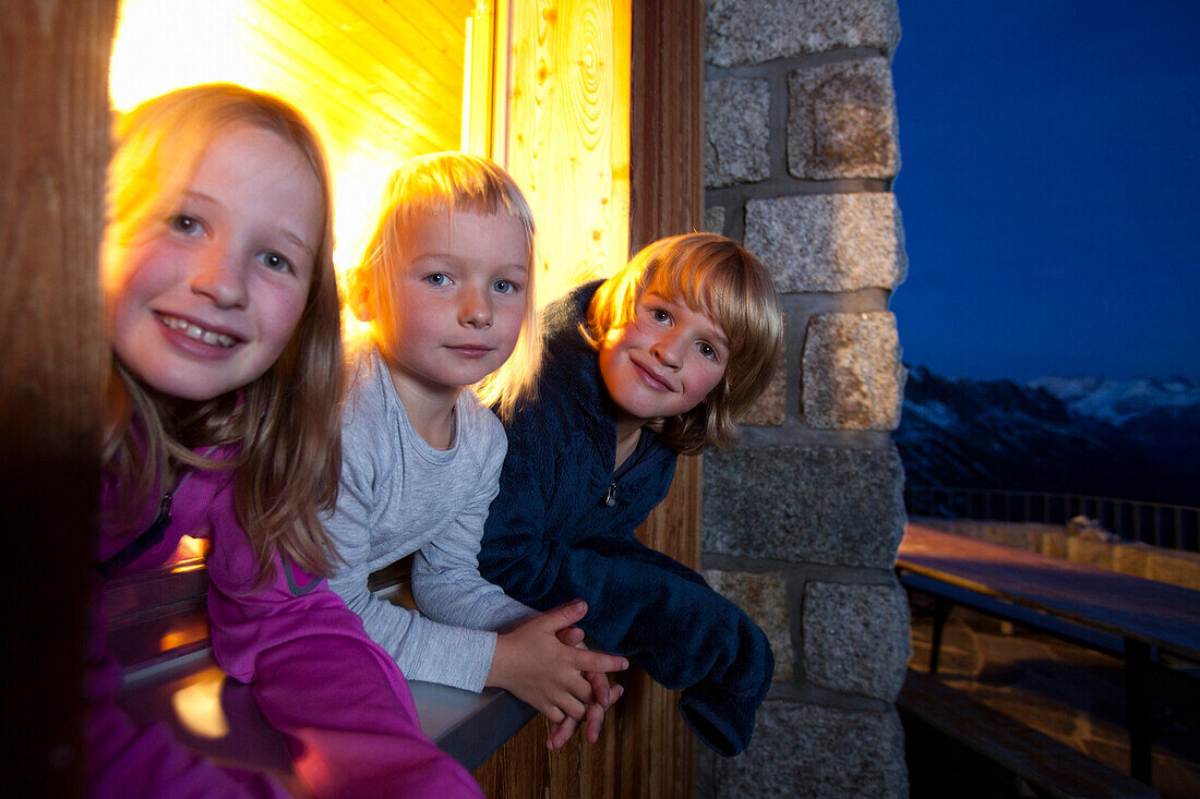 Zwei Mädchen und ein Junge am Abend in einer Berghütte, Sewenhütte, SAC Schweizer Alpen-Club, Alpen, Kanton Uri, Schweiz
