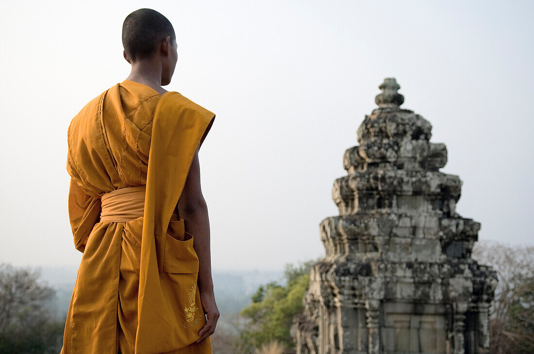 Buddhist Monk standing on hill top next to Bayon Temple, Cambodia, Angkor Wat.