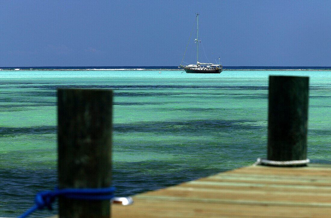Sailboat moored in turquoise waters beyond a pier, Grand Cayman Island