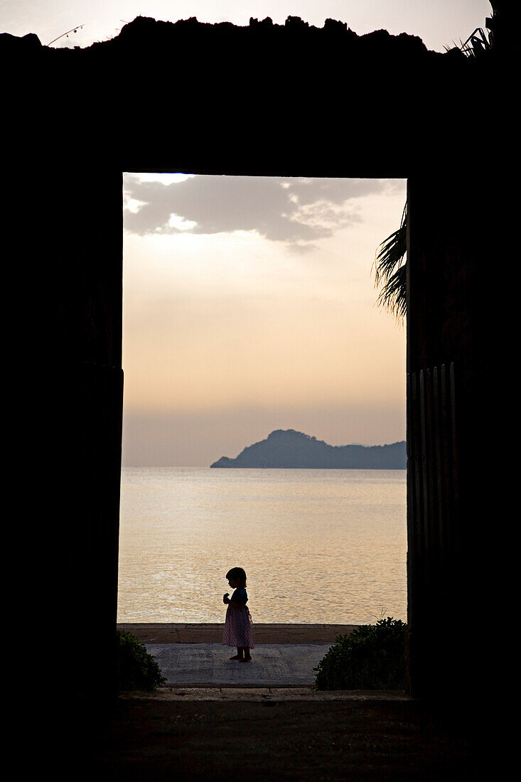 View through a doorway at the silhouette of a little girl on Lopud island, Elafti Islands, Croatia.