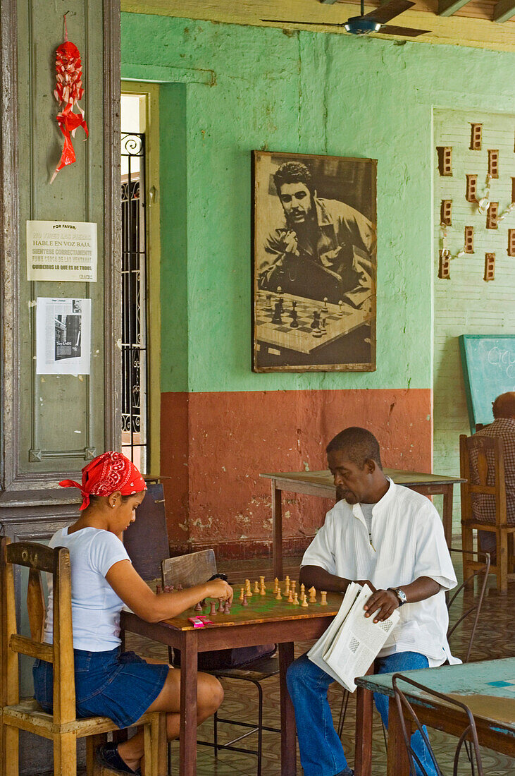 Locals playing chess at a chess club, with a poster of Che Guevara in the background, Santiago de Cuba, Cuba
