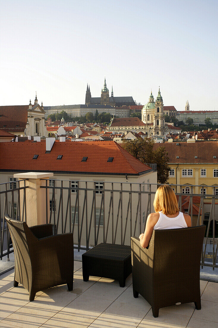 Woman sitting on roof terrace overlooking Prague castle, Prague, Czech Republic