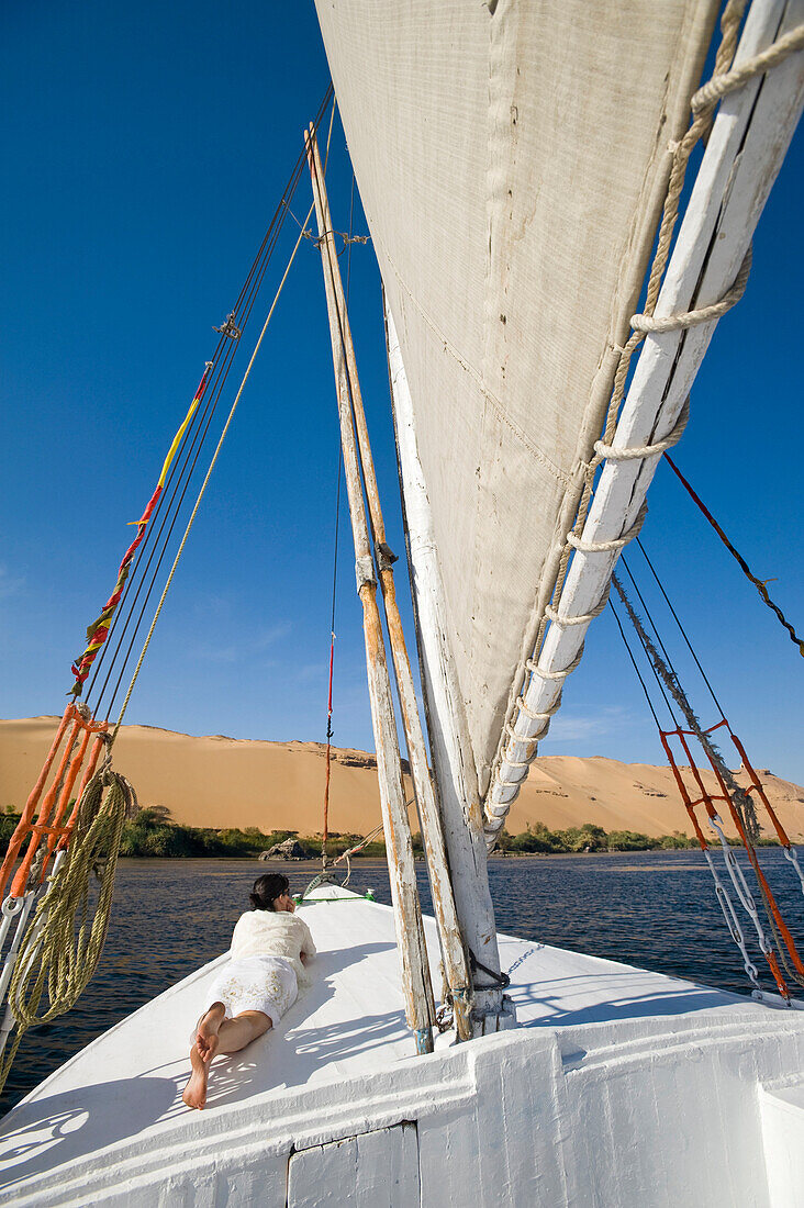 Woman relaxing on deck of felucca, River Nile, Aswan, Egypt
