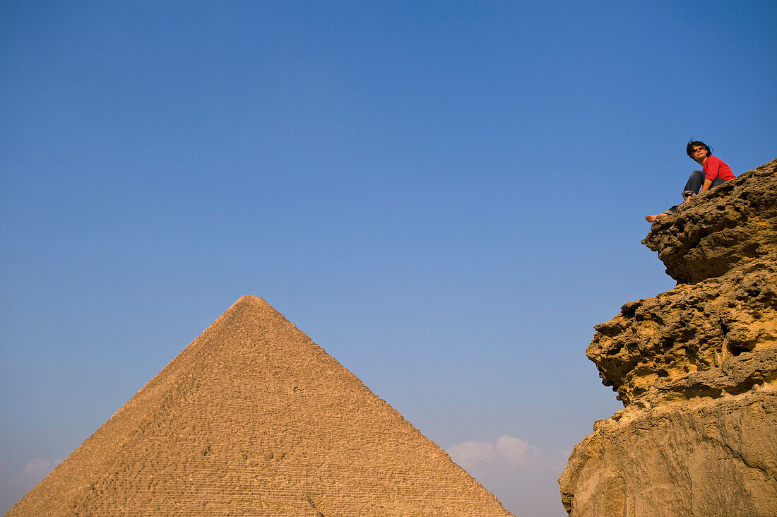 Woman on rocky outcrop looking over Pyramids, Giza, Cairo, Egypt
