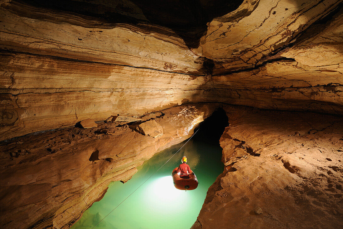 Speleology, caving, caver on a boat on an underground river, Event de Brun (Gard, France)