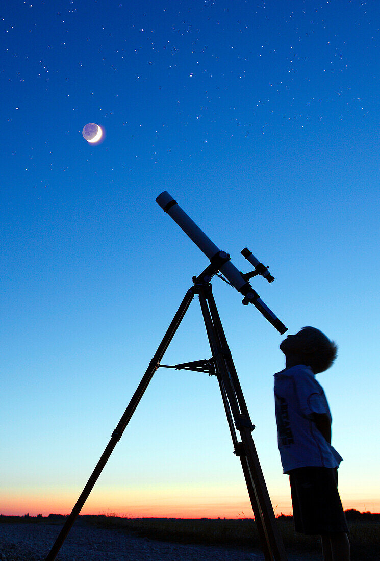 Little boy looking at moon with telescope