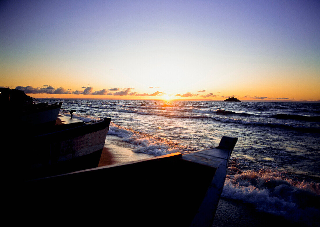 Man washing in the surf at dawn beside fishing boats, Senga Bay, Lake Malawi, Malawi