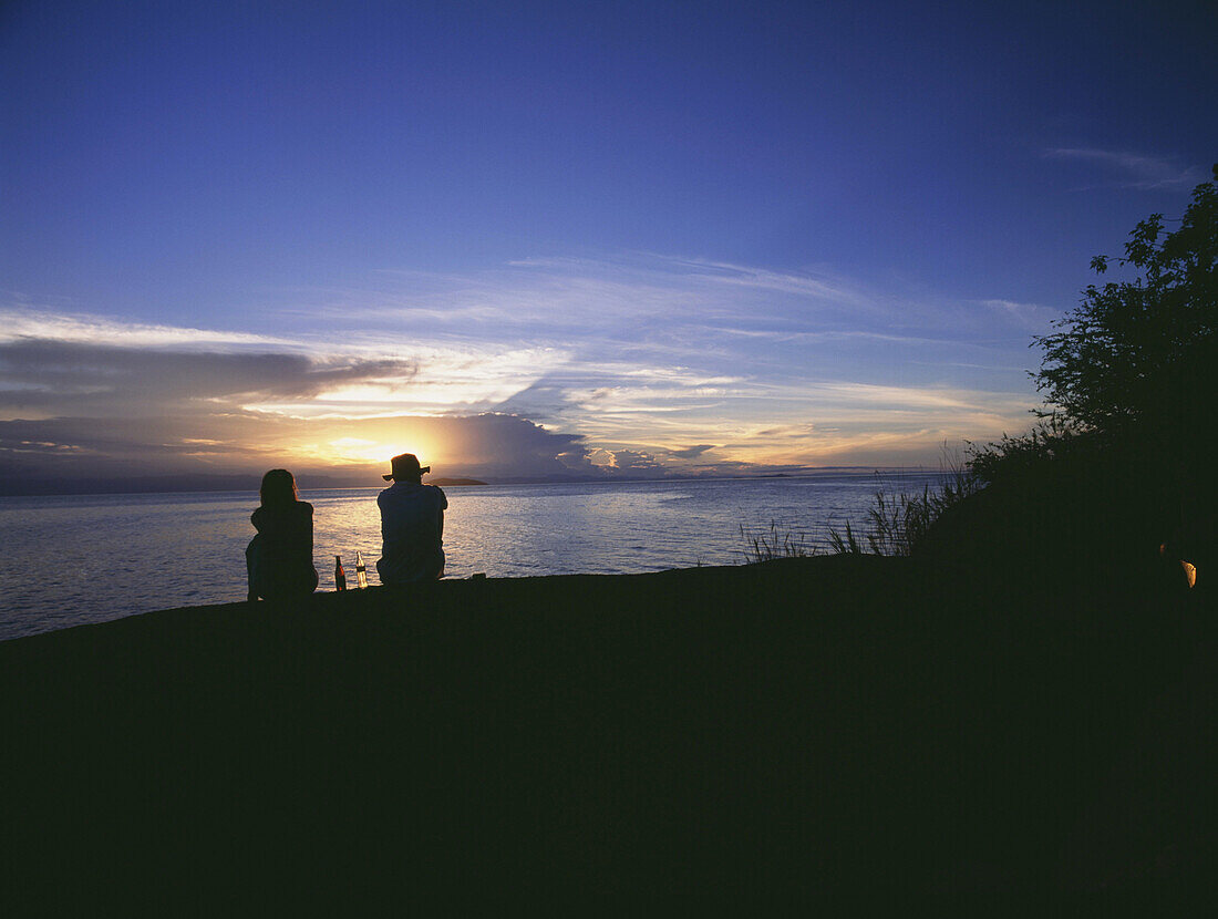 Couple having sundowner drinks at sunset on Domwe Island, Lake Malawi, Malawi