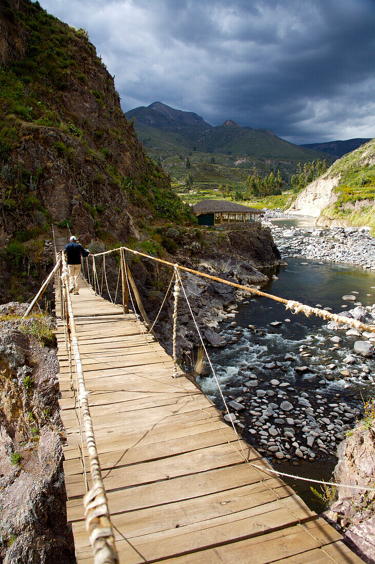 Person walking through suspension bridge in Colca Valley, Peru