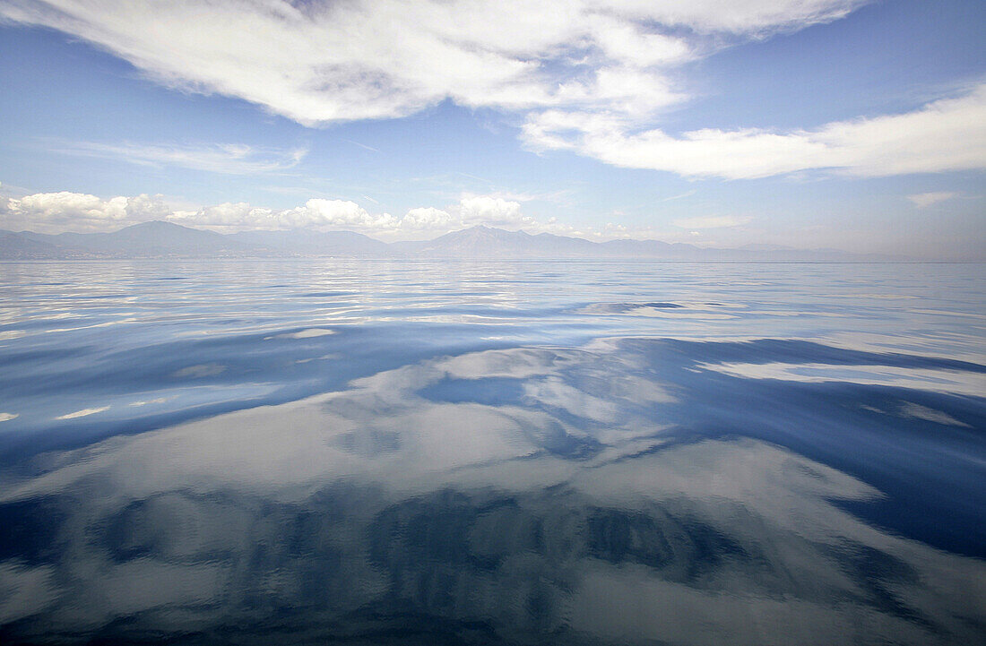 Very calm waters in the Mediterranean sea with the coastline and clouds in the background, Costa Del Sol, Spain