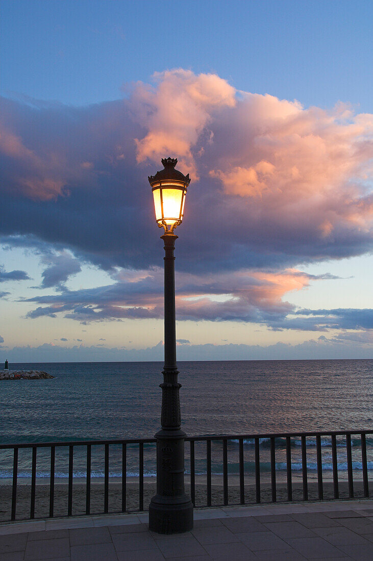 Street lamp with cloud above and sea behind, Costa del Sol, Marbella, Andalucia, Spain