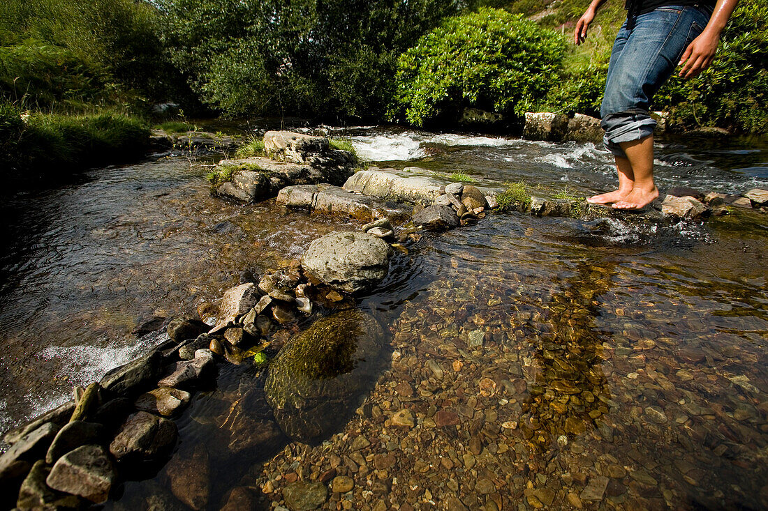 Woman crossing river in woods, Low Angle View, North Devon, Exmoor, England