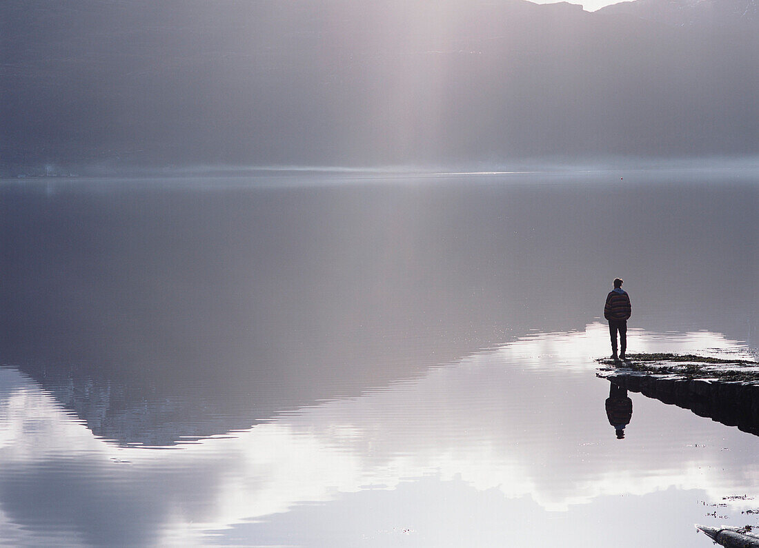 Woman standing on the end of a pier beside Loch Torridon, Ross-shire, Scotland