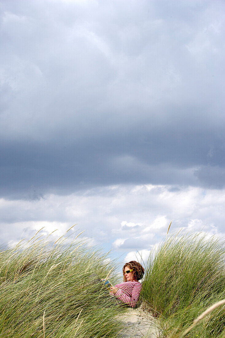 Woman reading on beach, Chichester, West Sussex, United Kingdom