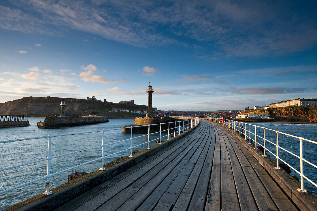 Looking back along pier to town and ruins of abbey, Whitby, North Yorkshire, England, UK