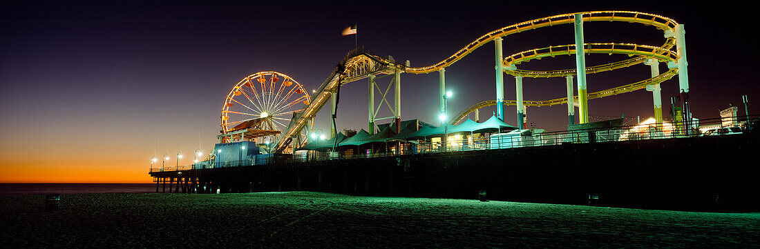 Rollercoaster and ferris wheel at dusk on the Santa Monica Pier, Los Angeles, California