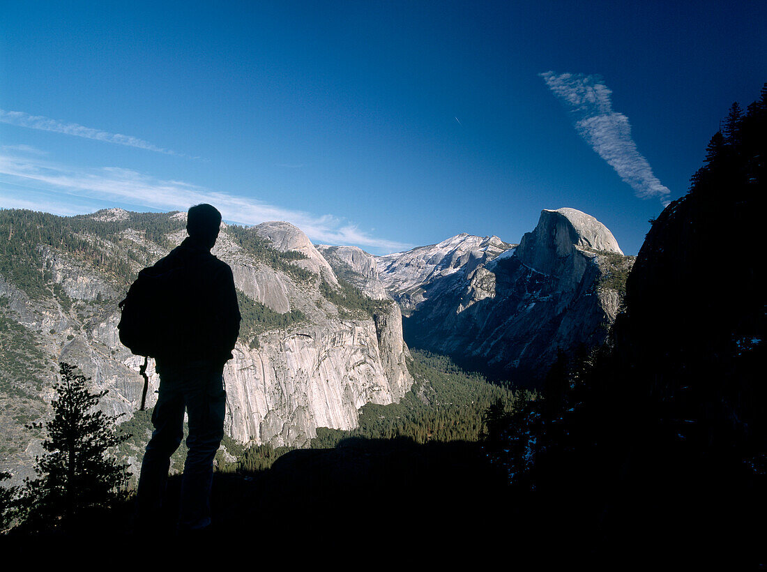 Silhouette of hiker looking towards Half Dome and the Yosemite Valley, Yosemite National Park, California