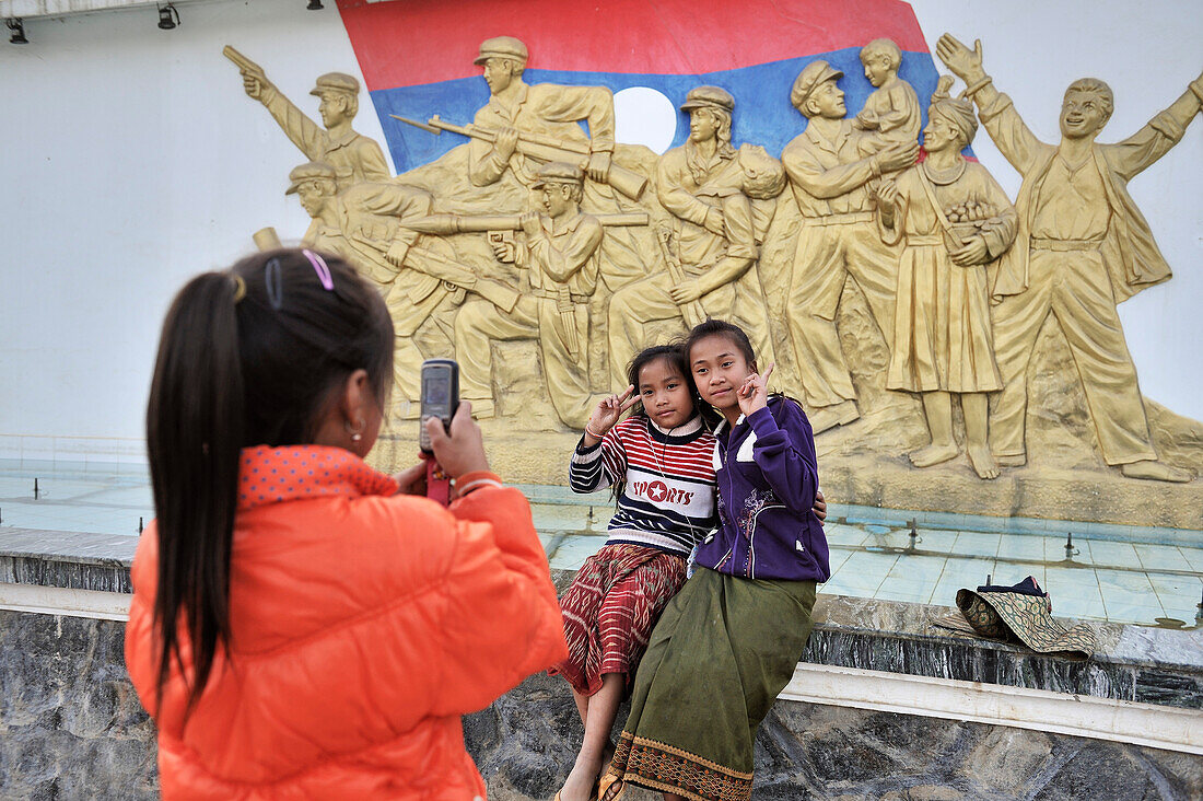 Young people of Laos posing for photo in front of a communist monument, Sam Neua, Highland Laos