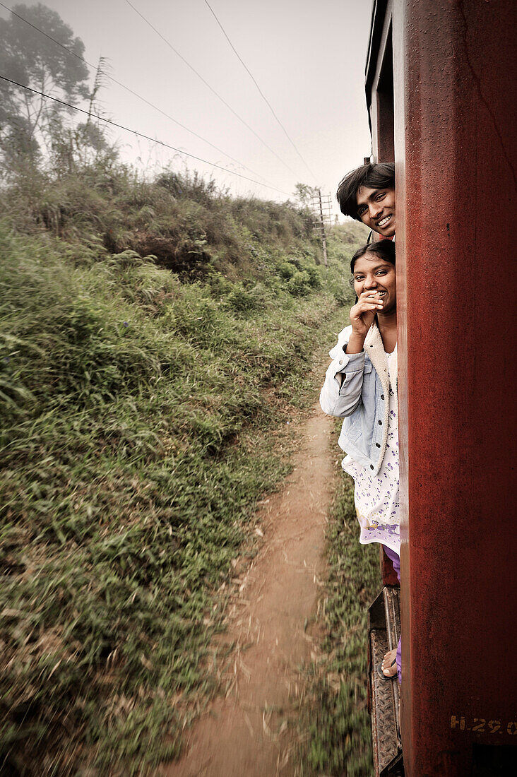 Erlebnis Reisen mit der Bahn, einheimische hängen aus Zug heraus, Haputale, Hochland Sri Lanka