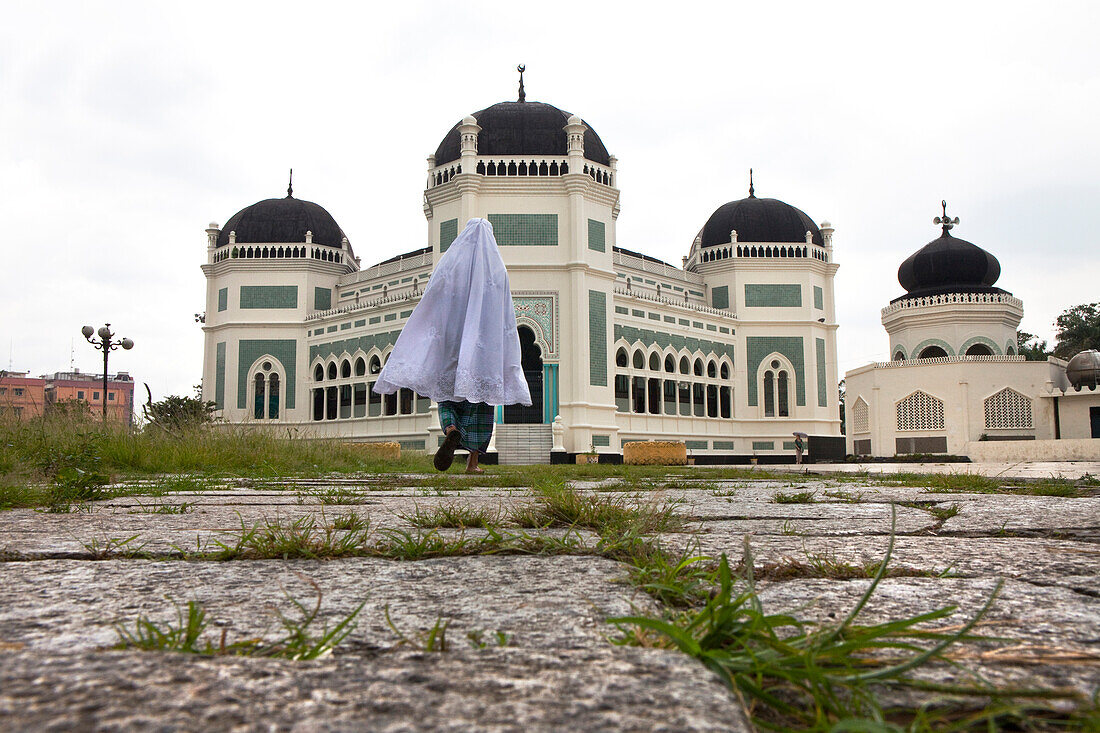 Muslim pilgrim in front oft he Grand Mosque in Medan, capital of Sumatra Utara province, Island of Sumatra, Indonesia, Southeast Asia