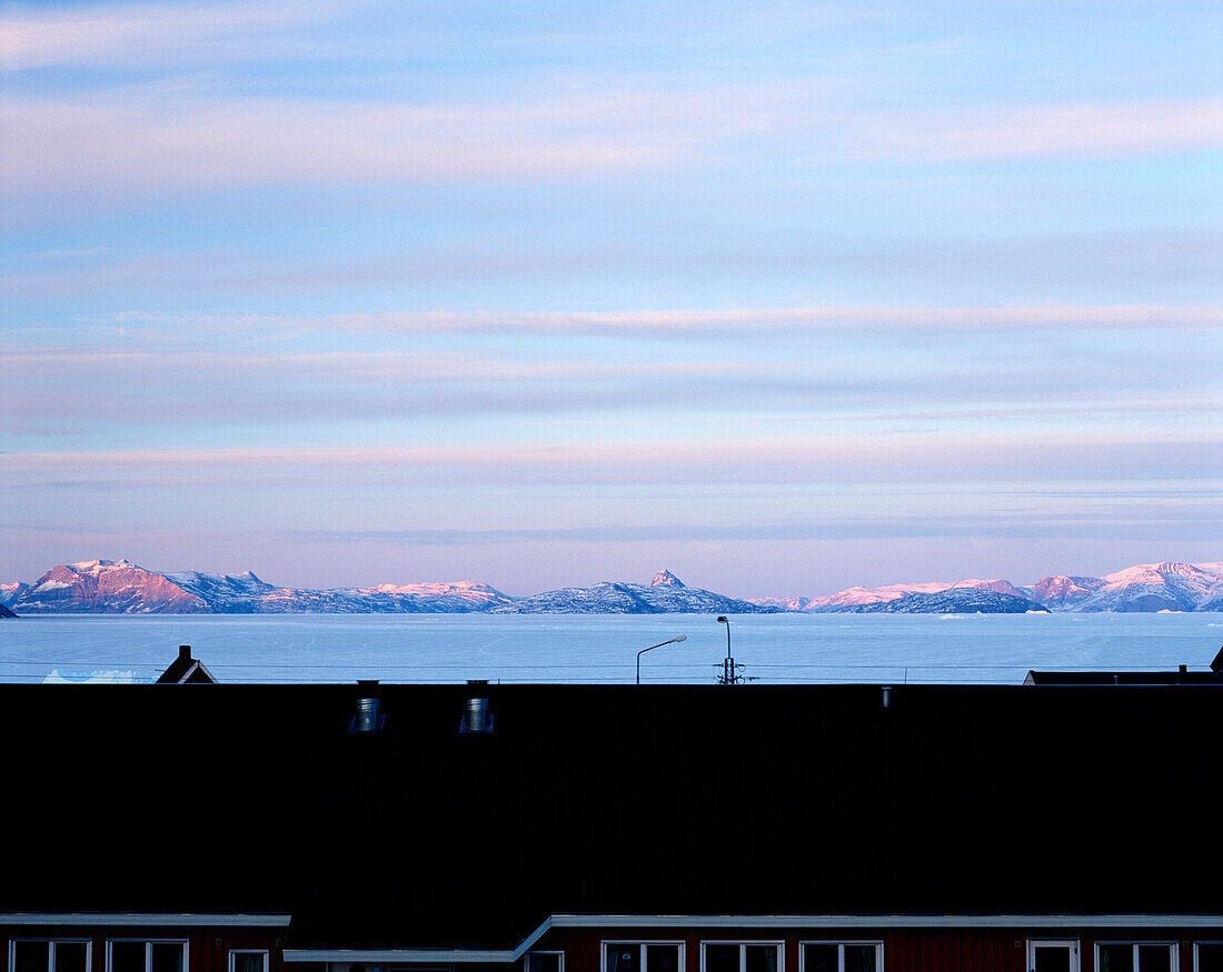 View over rooftop towards coastline and mountains, Uummannaq Island, Greenland