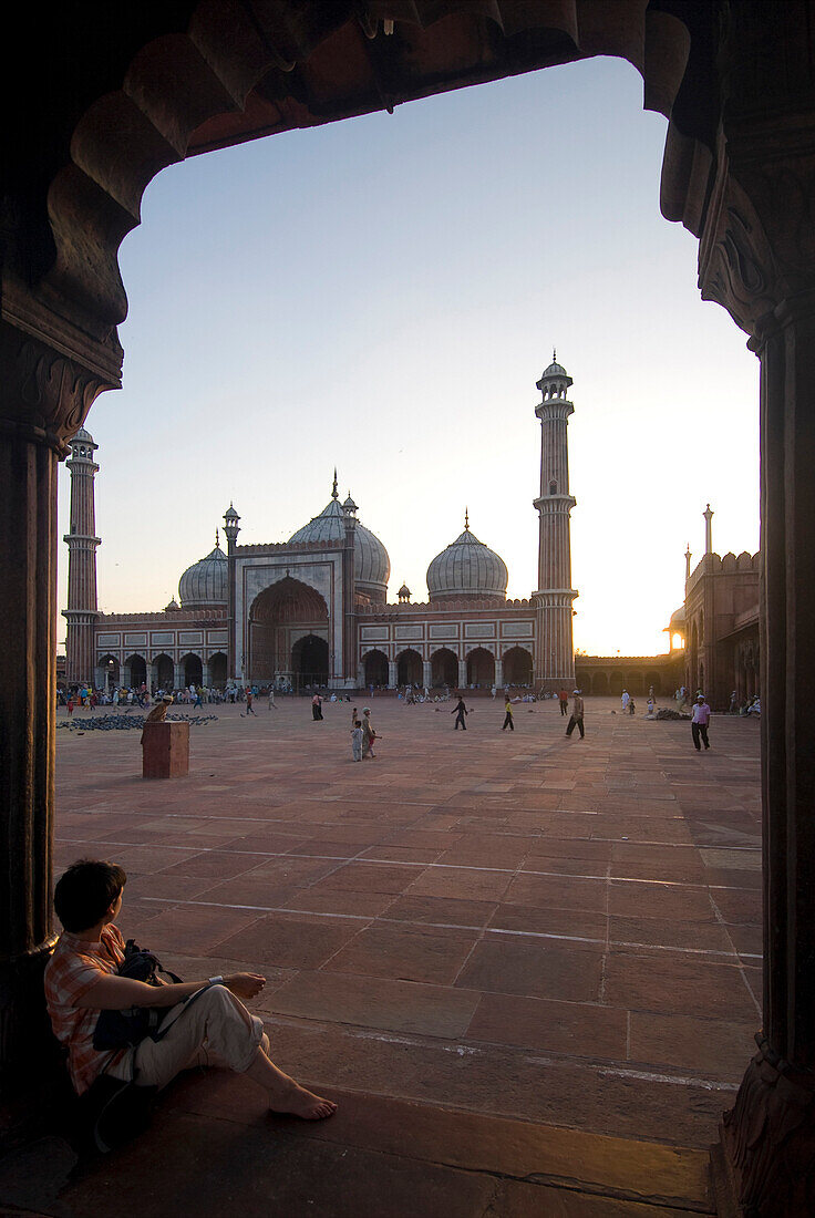 Tourist looking over the main courtyard of the Jami Masjid at dusk, Delhi, India