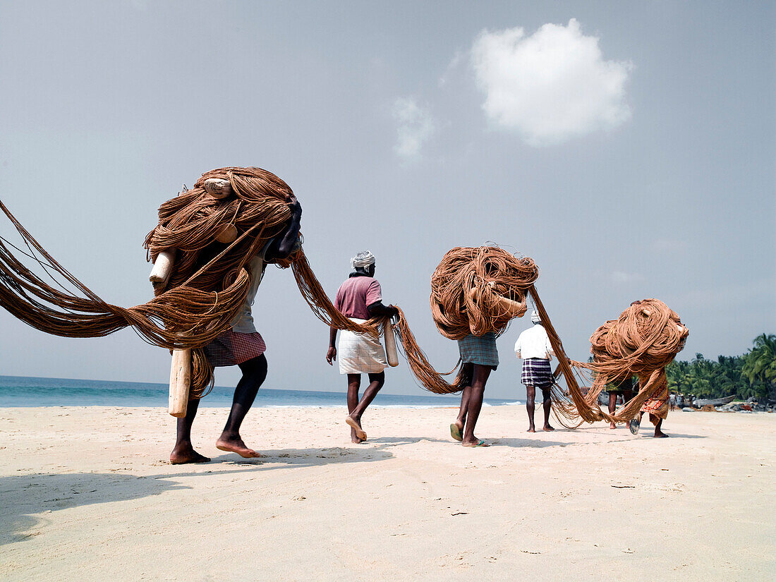 Fishermen carrying nets on beach, Varkala, Kerala, India