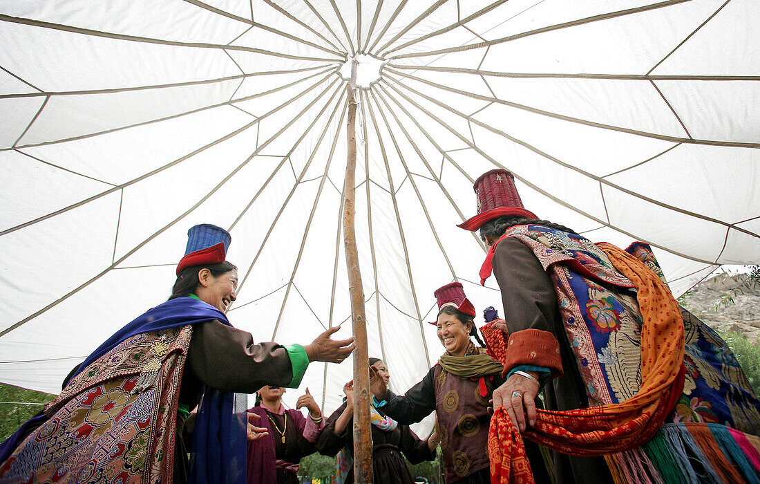 Ladakhi women in traditional dress and hats dancing under a traditional marquee, Leh, Ladakh, Indian Himalayas, India