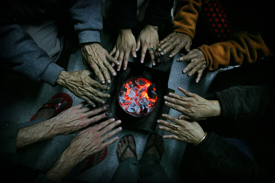 People warming their hands over a sikri, Close Up, Lunglei, Mizoram, North East states, India.  A sikri is a Mizo charcoal burner.