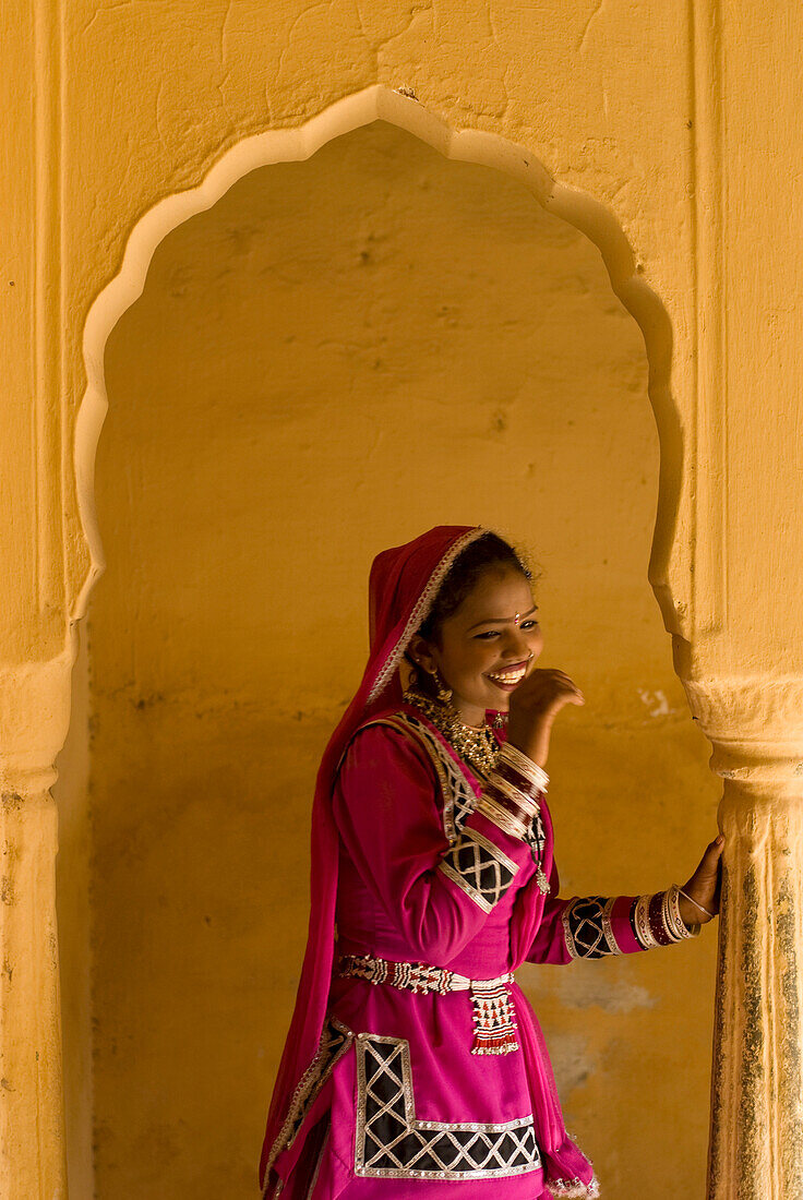 Laughing woman in traditional Rajasthani sari and jewellery in archway of old building, Jaipur, Rajasthan, India