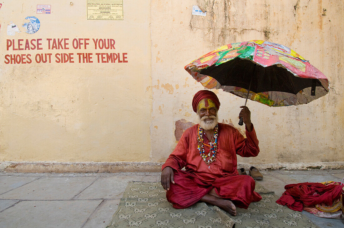 Sadhu with umbrella outside small temple, Jaipur, Rajasthan, India