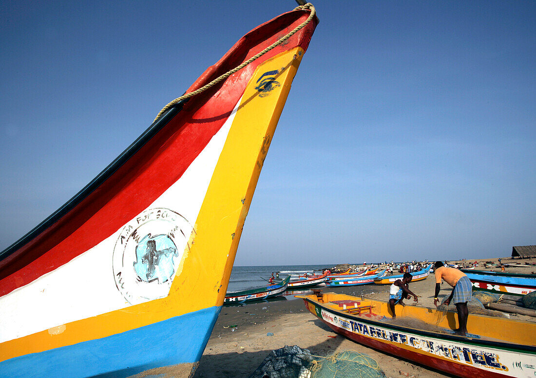 Colourful fishing boats on beach with fisherman in background, Tamil Nadu, India