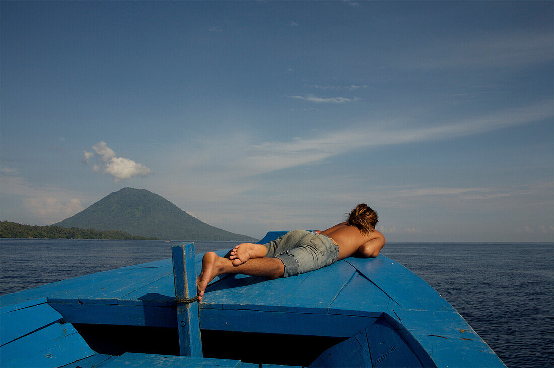 Man sunbathing on boat, Manado Tua, North Sulawesi