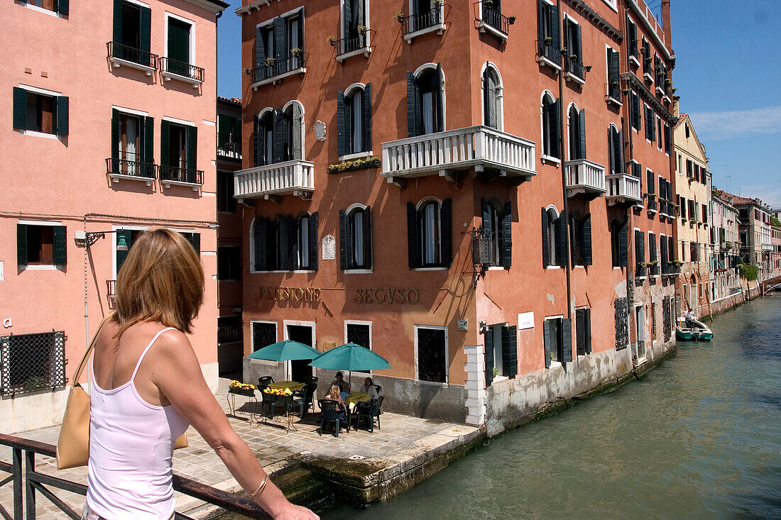 Woman on bridge overlooking canal, Venice, Italy
