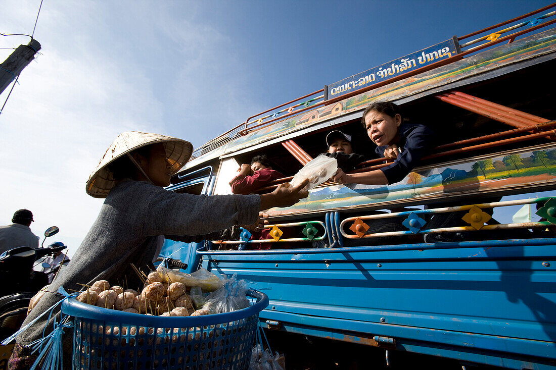 Woman offering food for sale on board ferry crossing the Mekong river, Si Phan Don in southern Laos