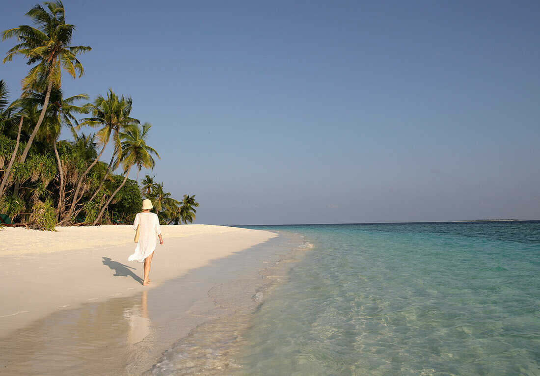 Young woman walking on the beach, Coco Palm Dhuni Kolhu Island, Maldives.