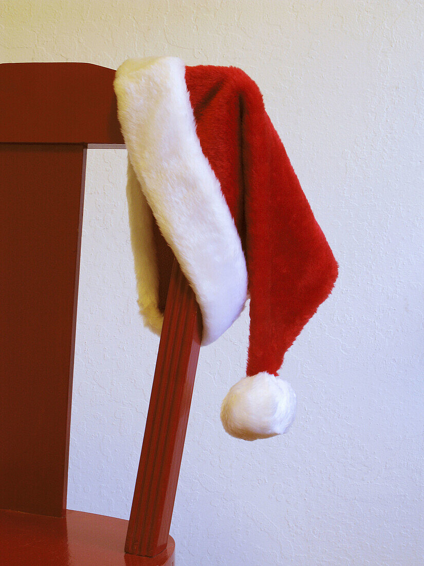 Santa Claus hat hanging on the back of a red chair