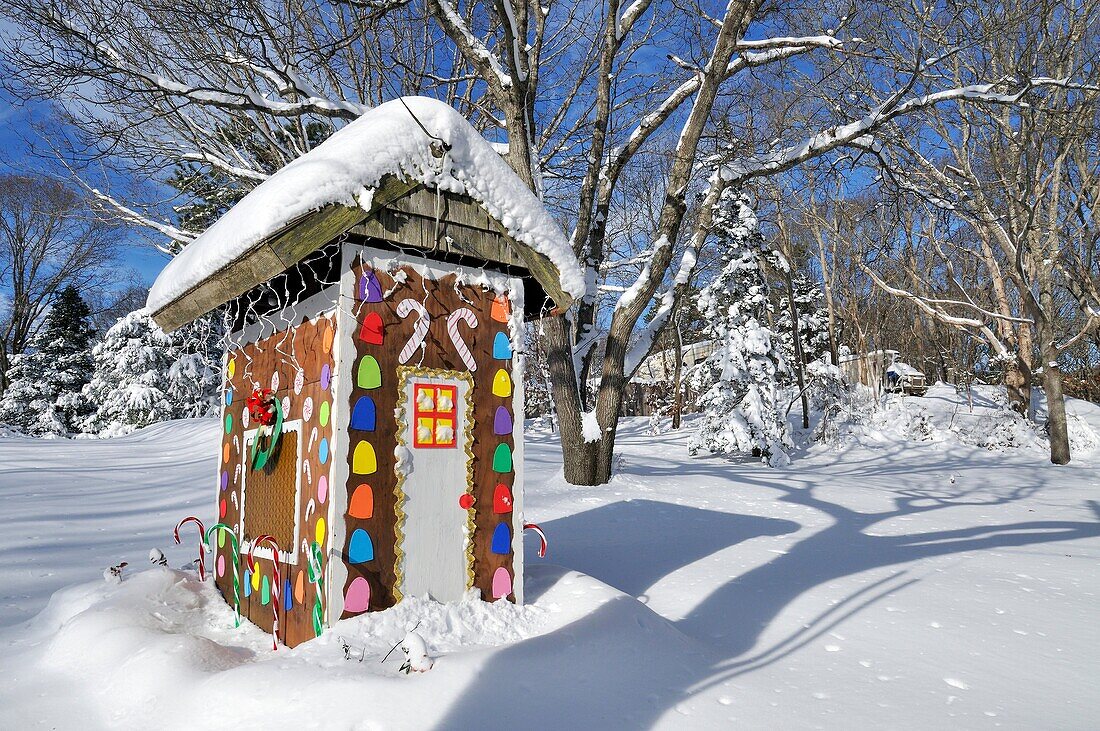 Colorful wooden gingerbread house decorated for the Christmas holidays after a fresh snow on a clear blue sky day on Cape Cod.