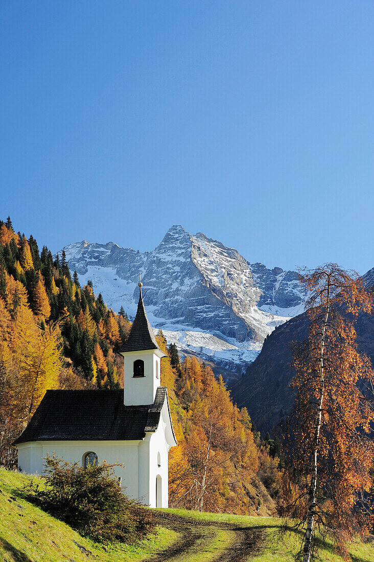 Chapel with autumnal forest and Fussstein in the background, valley of Valsertal, Zillertal range, Tyrol, Austria, Europe