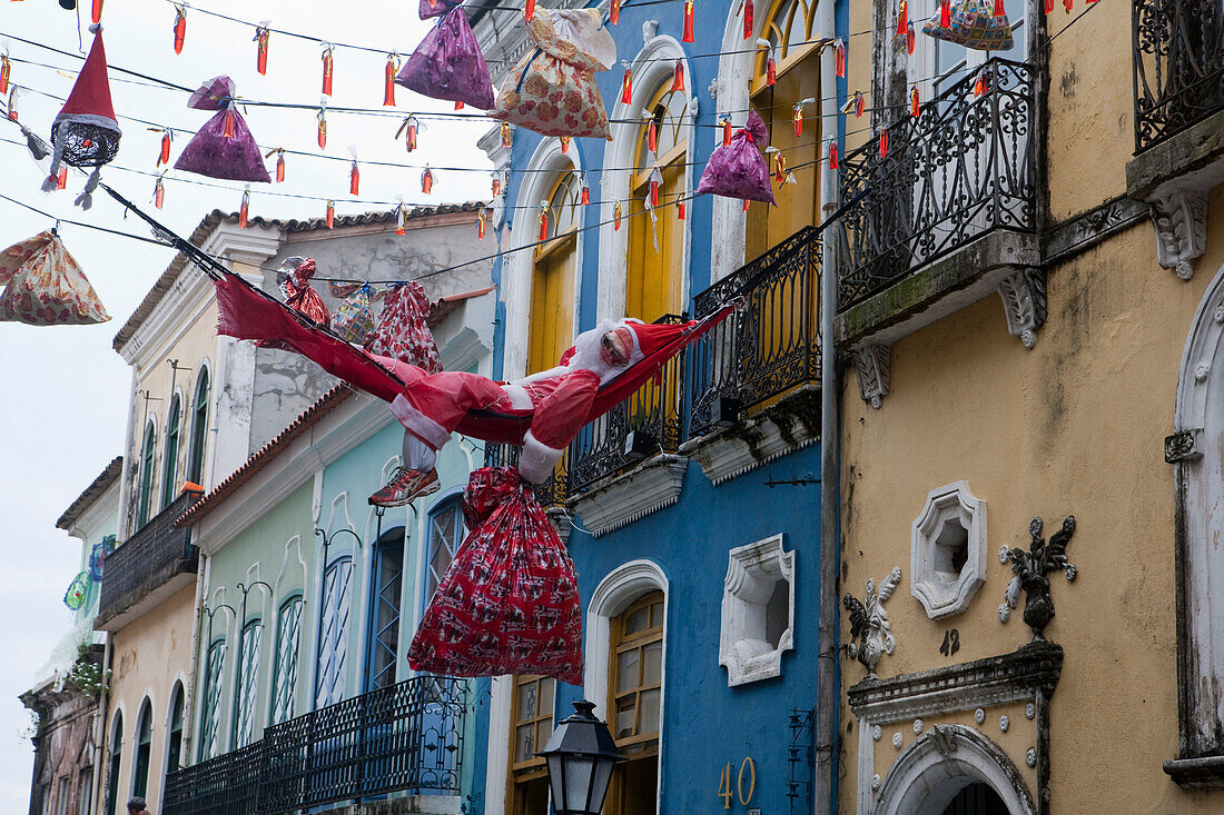 Santa relaxes in hammock between colorful buildings in Pelourinho old town, Salvador, Bahia, Brazil, South America