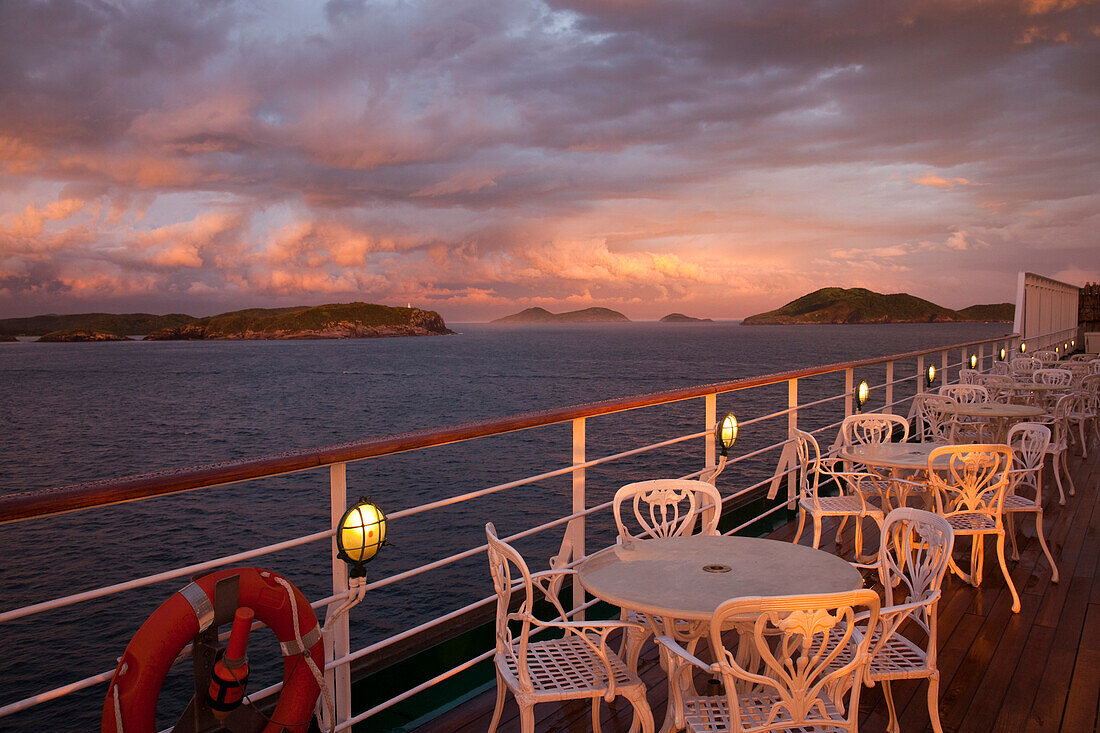 Tables and chairs on deck of cruise ship MS Deutschland, Reederei Peter Deilmann, with storm clouds at sunset, Cabo Frio, Rio de Janeiro, Brazil, South America