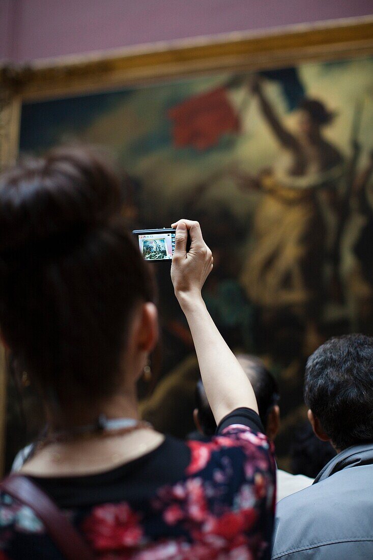 France, Paris, Musee du Louvre museum, 19th century French painting gallery, visitors photographing the painting Liberty Leading the People by Delacroix