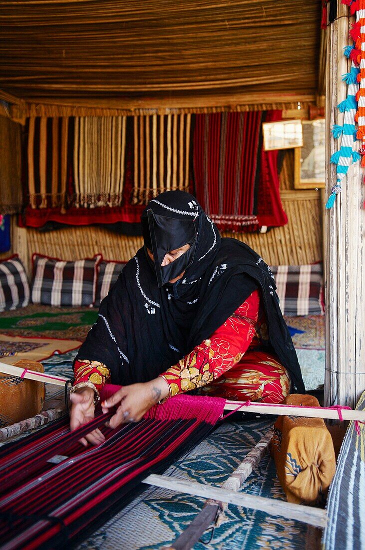 Middle East, Oman, desert of Wahiba, bedouins, woman working on carpet made for camels saddles.