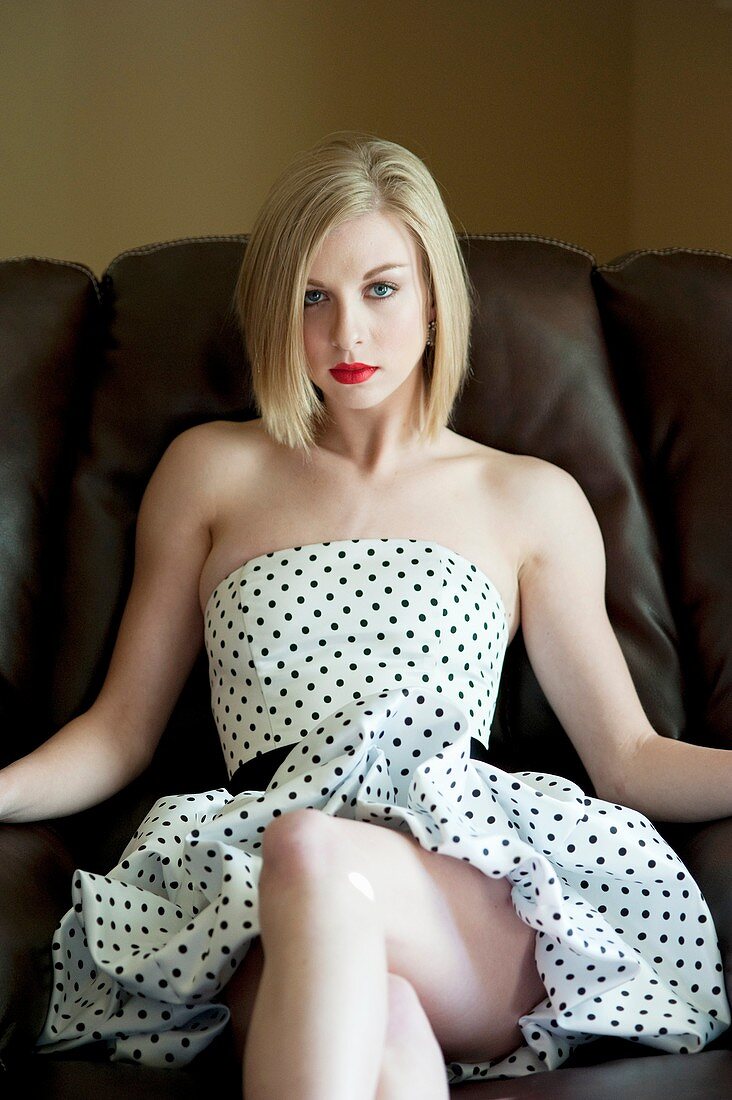 Portrait of a 19 year old blond woman sitting a in brown chair