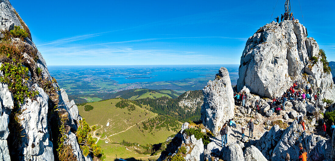 Visitors near summit cross, Kampenwand, lake Chiemsee in backgorund, Chiemgau, Upper Bavaria, Germany