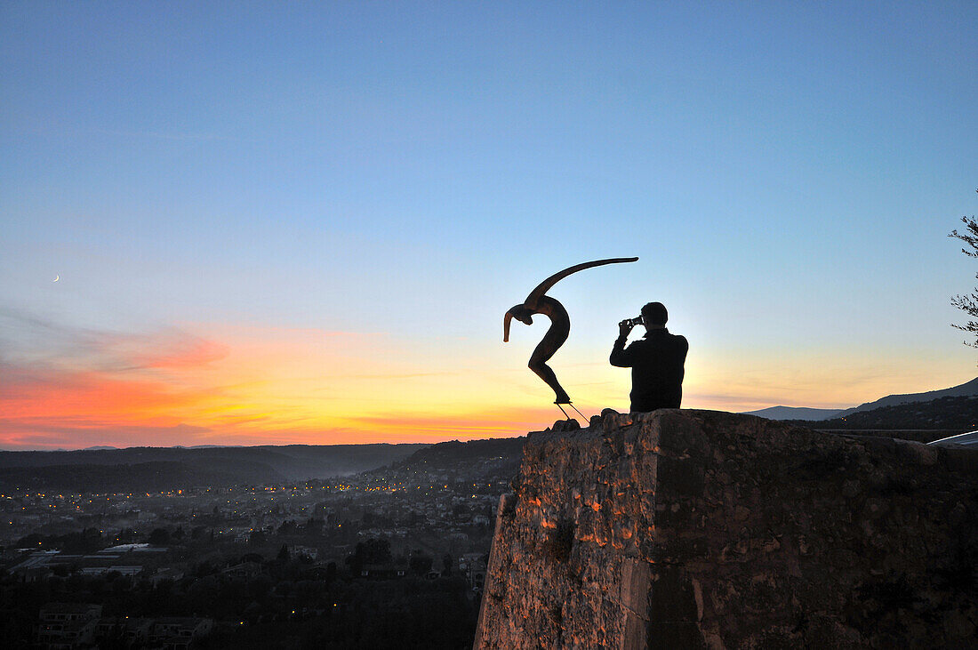 Mann fotografiert Statue bei Sonnenuntergang, Saint-Paul-de-Vence, Côte d'Azur, Süd Frankreich, Europa