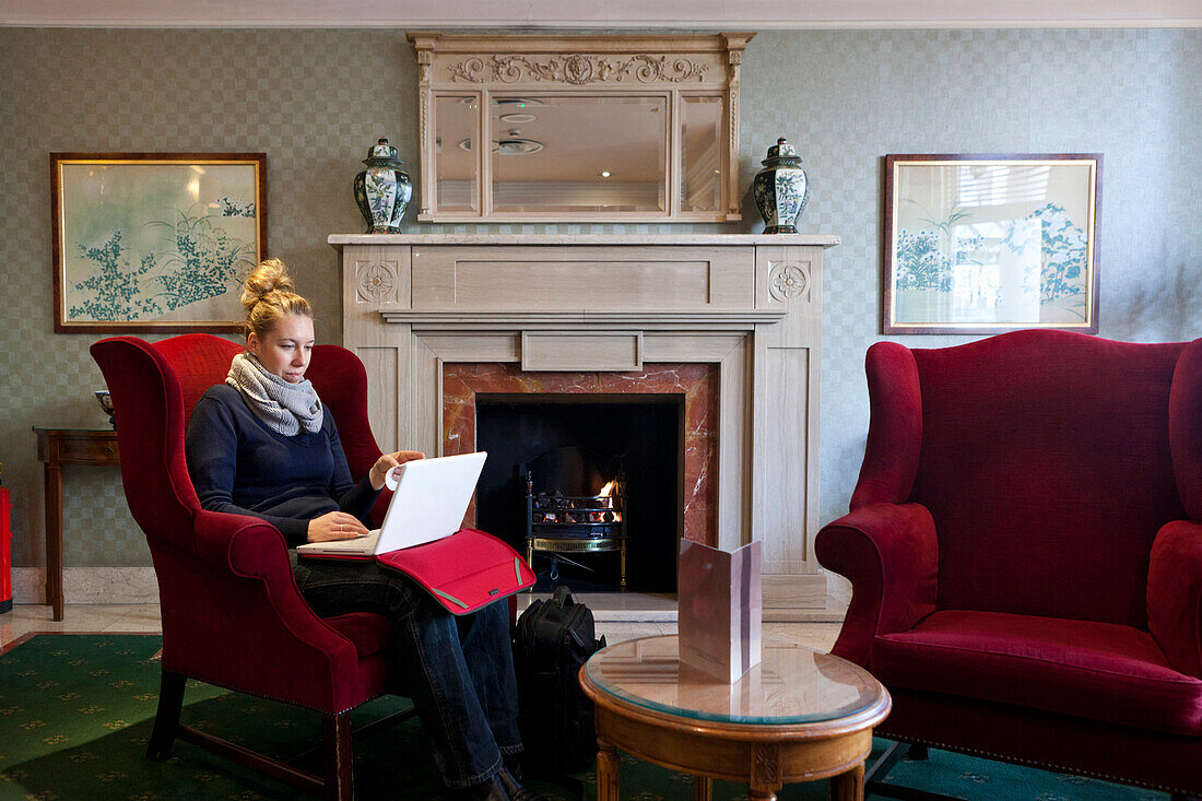 Woman enjoying a warm fire in an English sitting room, London, England